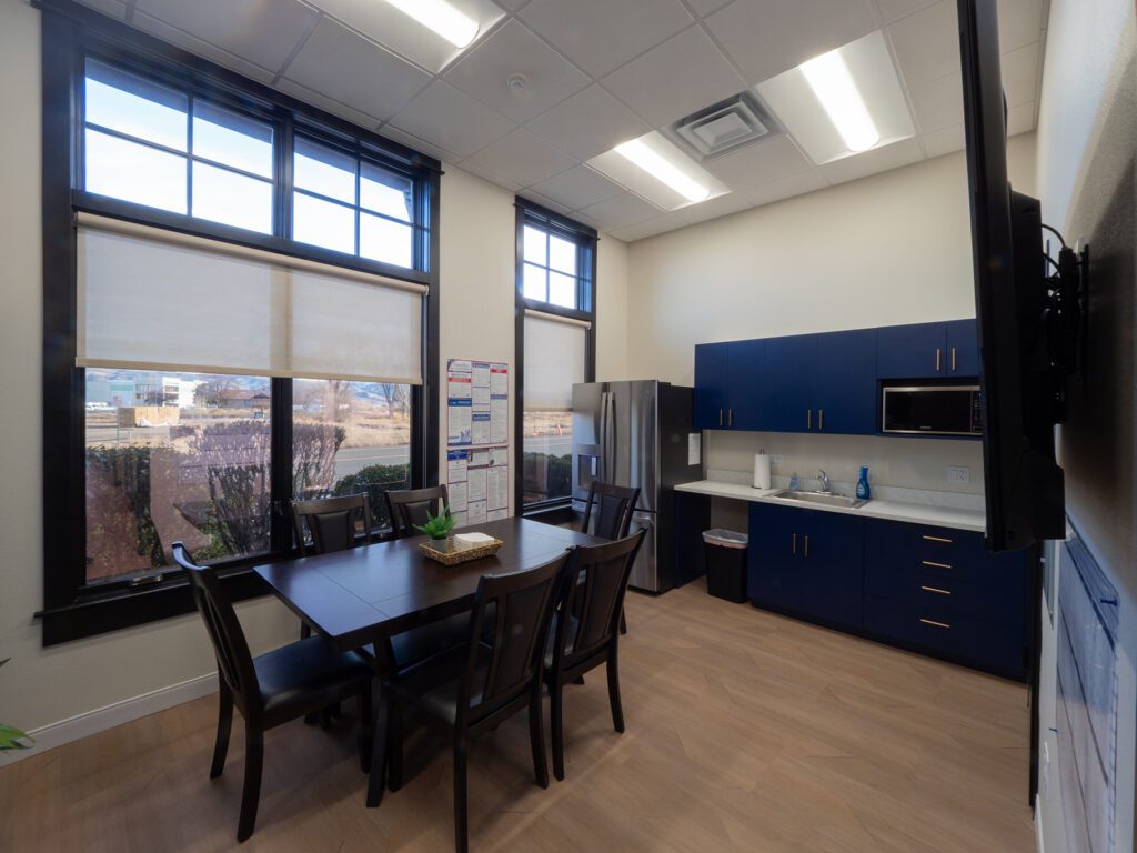 Renovated break room with table, fridge, and windows, completed by remodeling contractors Reno NV