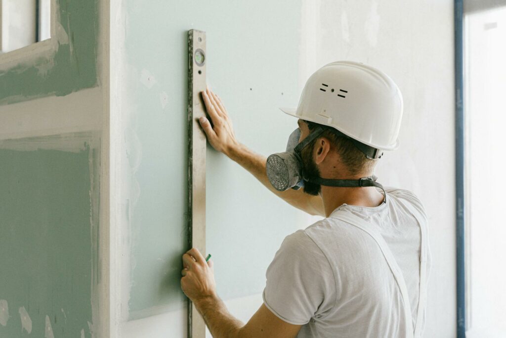 Construction worker using a level tool on a wall during office remodeling to ensure proper alignment in a commercial office renovation.