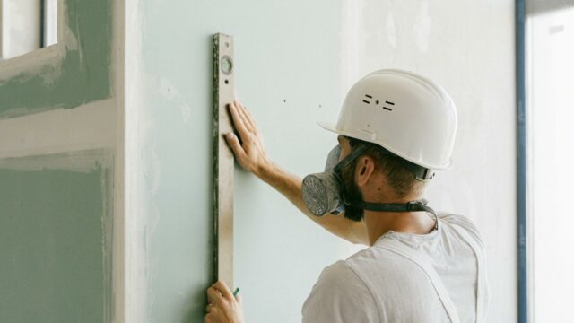 Construction worker using a level tool on a wall during office remodeling to ensure proper alignment in a commercial office renovation.